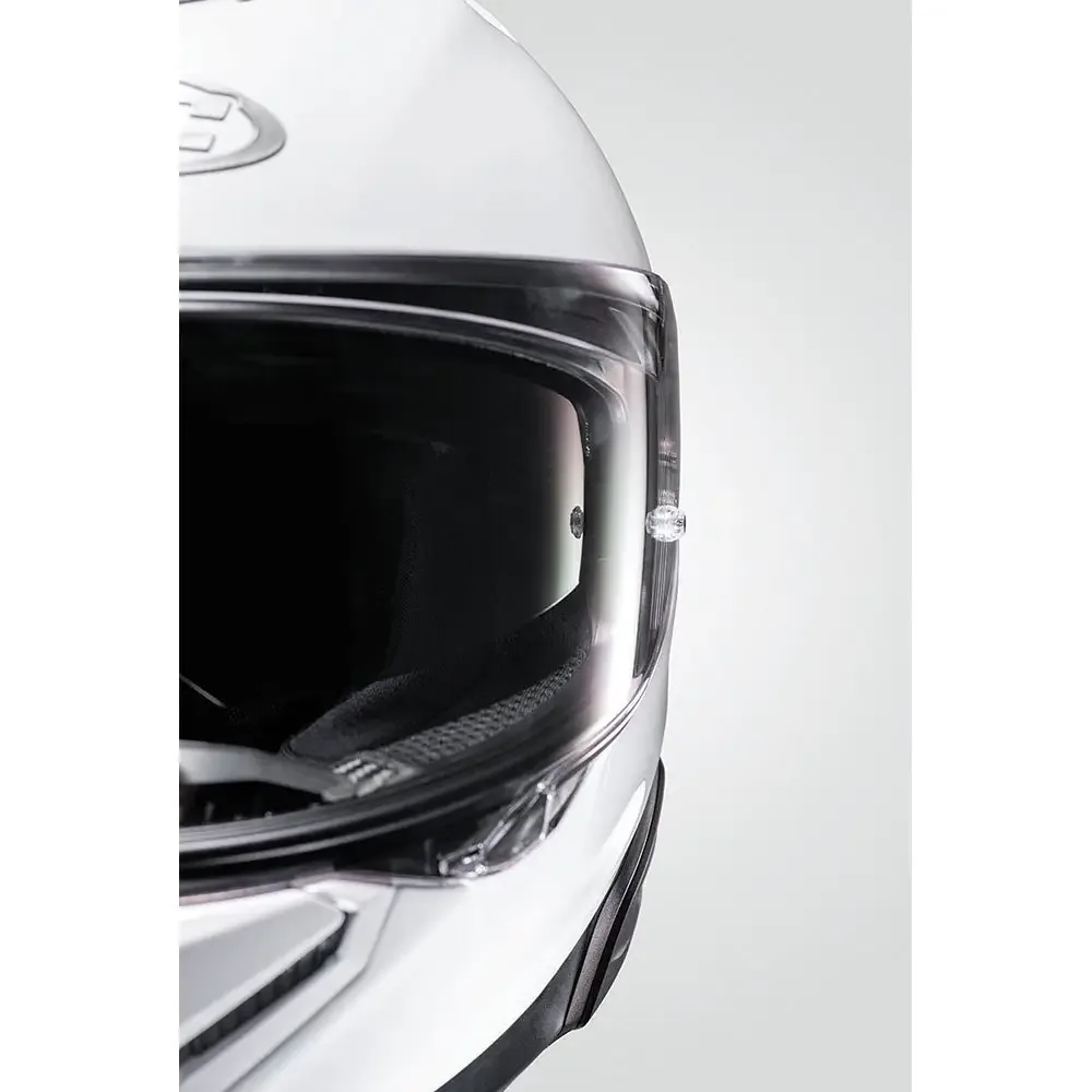 Primer plano de casco de motocicleta integral blanco con visor transparente y mecanismo de apertura lateral.